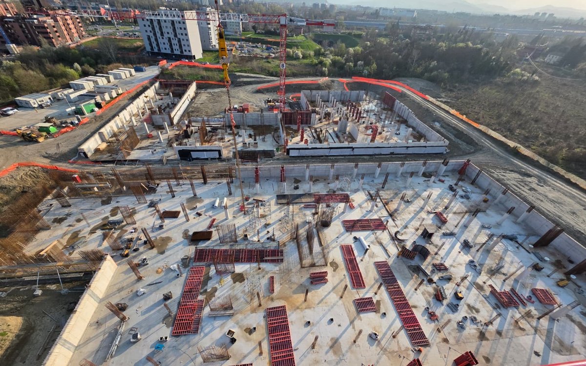 Grande cantiere strutturale con setti in c.a., casseforme e gru, vista aerea